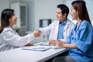 Three doctors shake hands in a hospital room