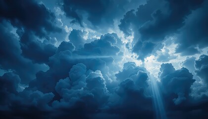 A dramatic sky filled with dark blue clouds and bright light shining through the cloudscape above