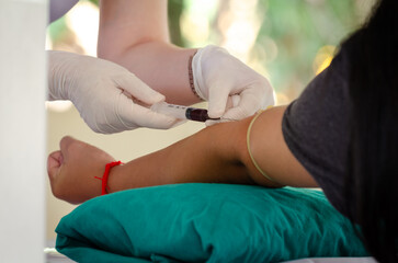 Close up nurse pricking needle syringe in the arm patient drawing blood sample for blood test ,...