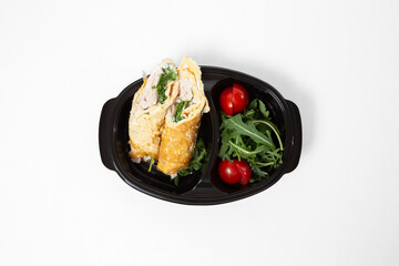 Omelette rolls with chicken and herbs, served with arugula and cherry tomatoes on a plate on a white background