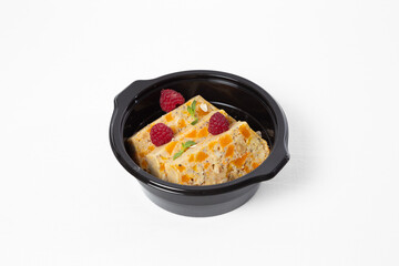 Oat dessert with nuts and pumpkin pieces, topped with fresh raspberries, served on a plate, on a white background