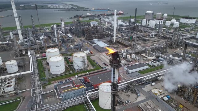 Aerial view of a chemical plant at sunset. Drone shot. Curling fire and cumin smoke filling the sky. Smoking chimneys from the factory. Chimneys of an oil refinery at sunrise pollute the environment