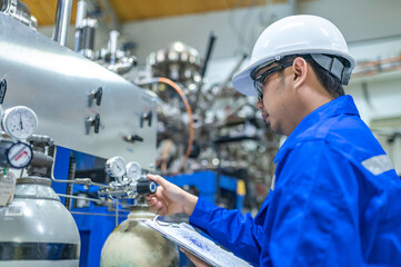 Asian engineer working at Operating hall,Thailand people wear helmet  work,He worked with diligence and patience,she checked the valve regulator at the hydrogen tank.