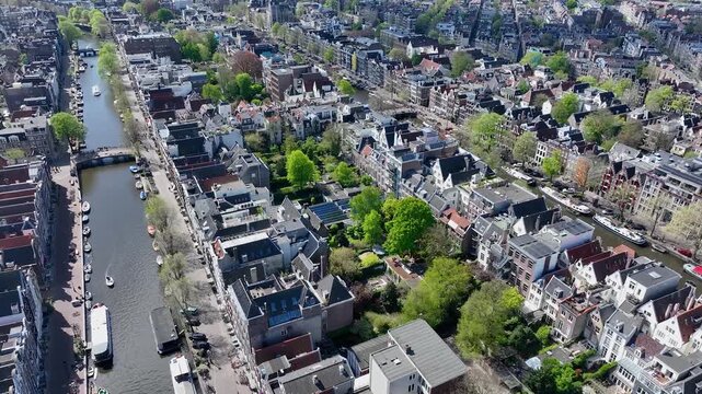 Beautiful aerial drone view from above, Amsterdam,  Netherlands. Narrow canals with bridges, street, boats, architectures lines of houses, famous sights and traffic around city downtown in Holland.4K