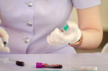 Blurred motion of nurse hand wearing white medical gloves shaking blood vessel for examining or...