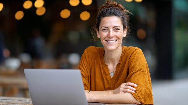 Happy female freelancer is working remotely in a cafe, enjoying work and travel lifestyle, using laptop for business or remote learning, representing digital nomad and work life balance concept