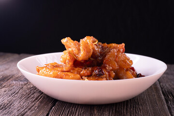 Fried chicken pieces in a sweet and spicy sauce on wooden background. Chinese food. Asian cuisine