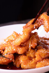 Fried chicken pieces in a sweet and spicy sauce on wooden background. Chinese food. Asian cuisine