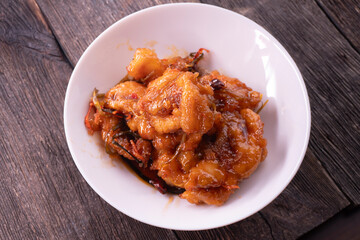 Fried chicken pieces in a sweet and spicy sauce on wooden background. Chinese food. Asian cuisine
