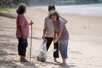A group of older people are picking up trash on the beach to help keep nature clean and beautiful.