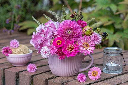 Blumen-Arrangement mit pink Dahlie, Zinnien, Federnelken und Hortensienbl&uuml;ten in einer Tasse 