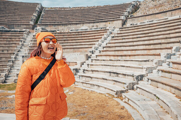 Girl testing echo and acoustics at ancient amphitheater, concept of sound in historical architecture