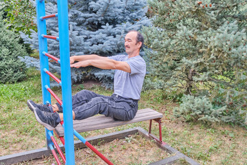 Senior man exercising on outdoor fitness bench in park