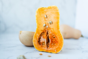 Halved butternut squash with seeds on marble surface.