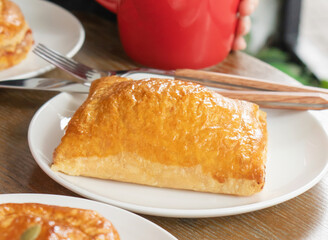 Sausage and Onion Puff Pastry in plate with Red Mug closeup view of Savory baked pastry