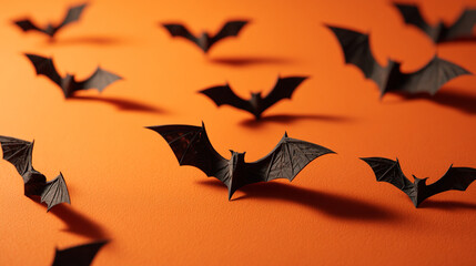 Naklejka premium A halloween themed background with black paper bats on an orange colored surface in a studio shot