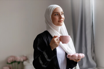 beautiful muslim woman in religious clothes drinking tea