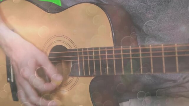 On cue musician's hand strumming guitar with rising speed and floating bokeh to showcase chords