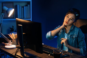Young beautiful Asian businesswoman taking break with stretching body with ache symptom for relaxing muscle after finishing overworked load report at neon light modern office at night time. Stratagem.