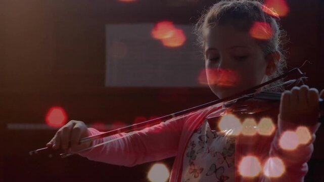 Student musician lifting violin and practicing bow strokes under bokeh lights in rehearsal hall