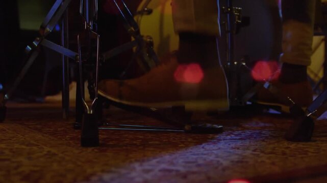 Drummer's right foot pressing pedal with ball of foot, driving bass drum beater and accenting beats