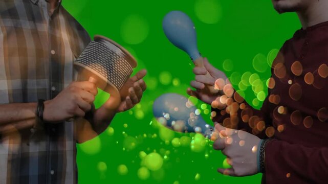 Musicians rotating cabasa and shaking maracas on green screen initiating bokeh for music production