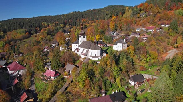 Flying over of fortified church in picturesque historic village Spania Dolina at autumn morning, Slovakia.
