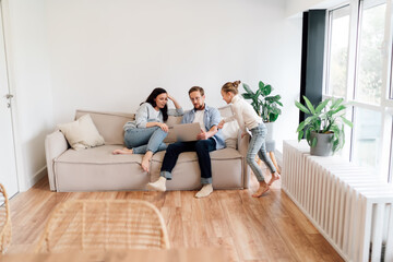 Obraz premium Parents sit close as daughter looks ahead, illustrating family unity, listening presence, and trust within everyday moments of emotional growth.