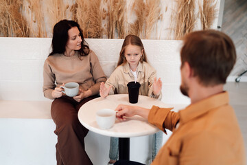 Girl speaks confidently as both parents watch, reflecting respectful parenting, verbal freedom and a warm space free of devices and digital interference.