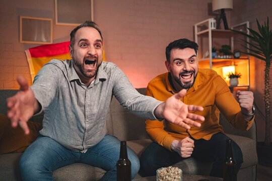 Excitement fills the room as friends cheer for their team during an intense sports match at home on a cozy evening