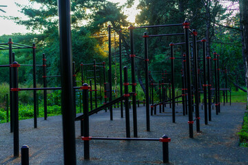 Fototapeta premium Outdoor fitness area featuring exercise equipment surrounded by trees during sunset in a quiet park