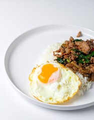 Savory stir-fried beef with basil, fluffy rice, and a perfectly fried egg on a white plate