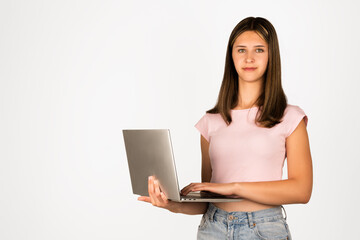 Naklejka premium Teenage girl with straight brown hair wearing a pink t-shirt and denim shorts holds a laptop, isolated on white background. Suitable for technology, education, online learning, remote work, and youth