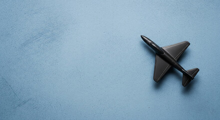 Tiny Black Airplane Model on Blue Textured Background
