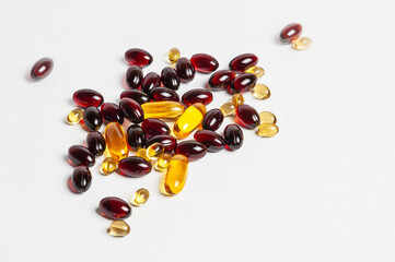 A close-up of various red and yellow capsules scattered on a white surface.