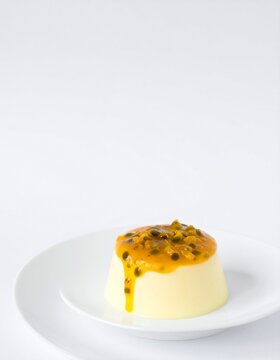 Indulgent creamy panna cotta crowned with vibrant passion fruit topping on elegant white plate