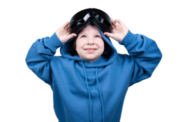 A happy young child wearing a blue hooded sweatshirt is putting on a black VR headset, looking upwards with a smile, isolated on a transparent background