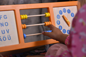 Little girl playing with colorful abacus counting frame