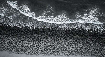 Aerial view of basalt stones beach at a rocky shore, A dark textured landscape featuring basaltic cobblestones and crashing waves
