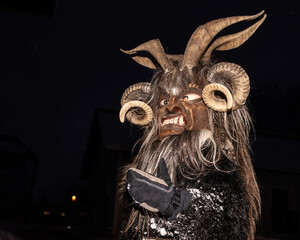 Traditional festival participant in elaborate horned mask during nighttime celebration in winter