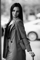 Young beautiful girl in an elegant suit with an umbrella outdoors. Black and white photo.