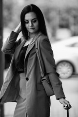 Young beautiful girl in an elegant suit with an umbrella outdoors. Black and white photo.