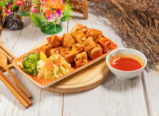 Stinky Tofu with Crispy, Sauced, Pickled Vegetables Cucumber, and Dip in tray side view of Taiwanese food