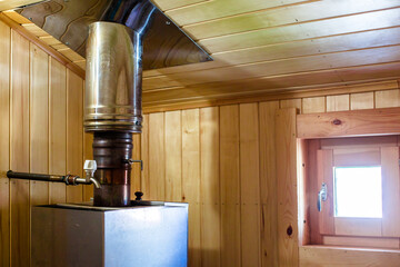 The big round stone furnace in a sauna. The walls trimmed with a red brick and a tree from natural...