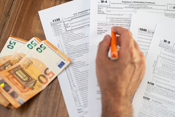 Company accountant hand holds pen preparing for filling different tax forms necessary for business...