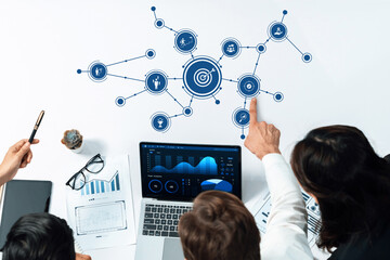 A modern office scene showcasing a collaborative team discussing business strategy and analytics with visual data charts and graphs displayed on a laptop. Amity