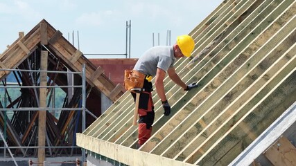 Worker Constructs Roof Framework at Construction Site During Bright Day