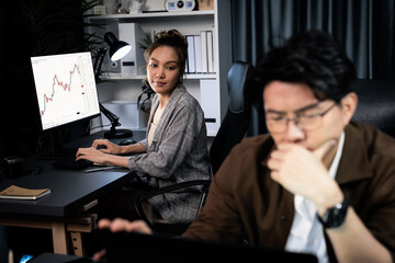 Businessman with stressful face working on laptop waiting email while coworker discussing together for consult at late night time at modern office, working on startup company project job. Infobahn.