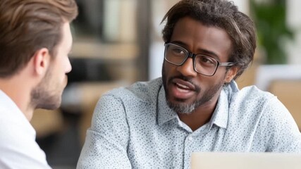 Two men in discussion, one wearing glasses, focusing on one speaker