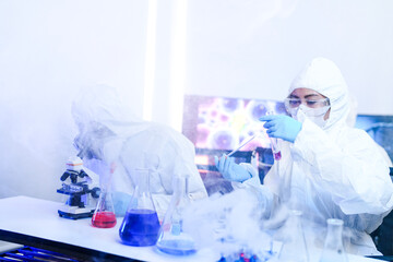 A team of chemists in hazmat suits discusses a breakthrough during a critical experiment in a...